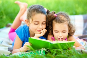 Девочки читают на траве