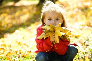 Девочка собирает осенние листья