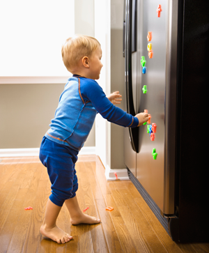 Ребенок играет с магнитами, прицепленными на холодильник
